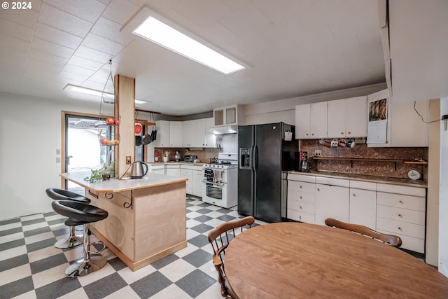 kitchen featuring light tile patterned floors, white cabinets, black fridge, range with two ovens, and decorative backsplash