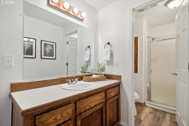 bathroom featuring vanity, toilet, hardwood / wood-style flooring, and walk in shower