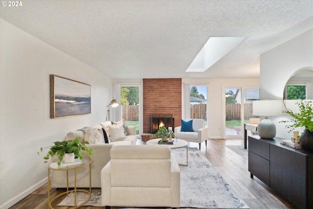 living room with a skylight, wood-type flooring, a textured ceiling, and plenty of natural light