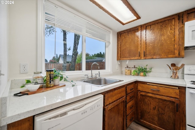 kitchen with sink, light stone counters, and white appliances