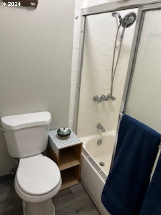 bathroom with washtub / shower combination, wood finished floors, and toilet