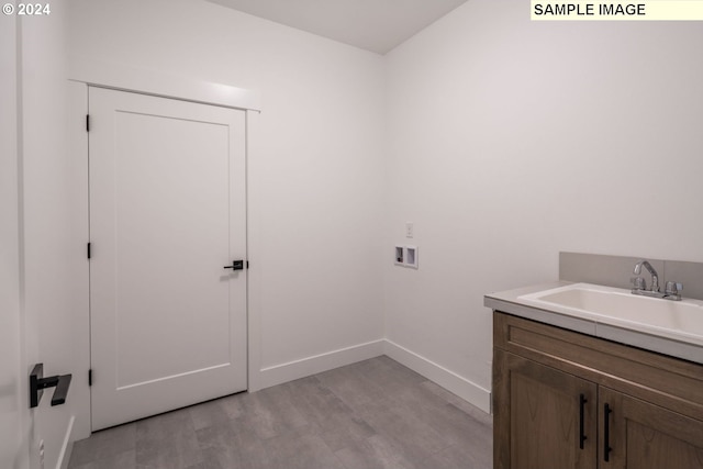 washroom with washer hookup, cabinets, sink, and light wood-type flooring