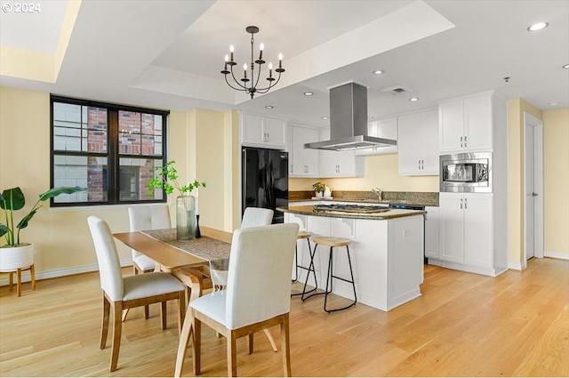 2442 NW Westover Rd Unit 3-202, Portland, OR 97210 - kitchen featuring freestanding refrigerator, island exhaust hood, a center island, baseboards, and white cabinets
