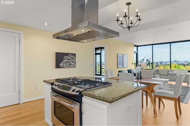 2442 NW Westover Rd Unit 3-202, Portland, OR 97210 - kitchen featuring island exhaust hood, stainless steel gas stove, open floor plan, light wood-type flooring, and white cabinetry