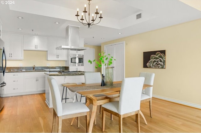 kitchen featuring ventilation hood, sink, pendant lighting, light hardwood / wood-style flooring, and white cabinetry