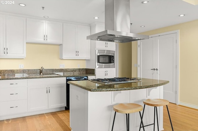 2442 NW Westover Rd Unit 3-202, Portland, OR 97210 - kitchen featuring island exhaust hood, a sink, appliances with stainless steel finishes, light wood-style floors, and a center island