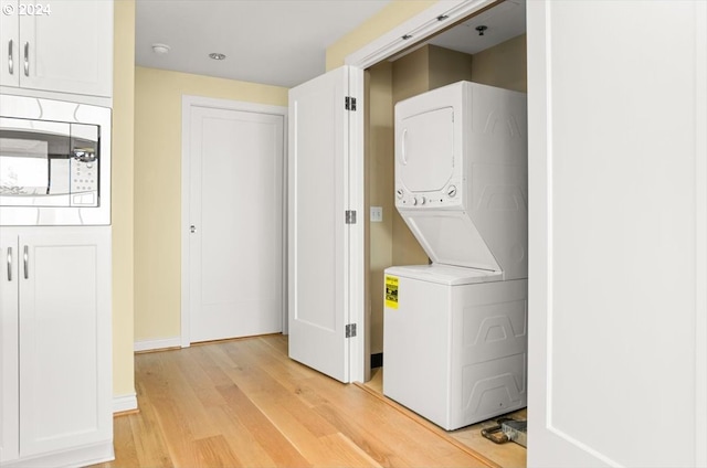 clothes washing area featuring light hardwood / wood-style flooring and stacked washer / drying machine