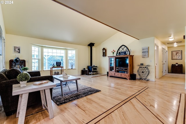 living room featuring hardwood / wood-style flooring, vaulted ceiling, and a wood stove