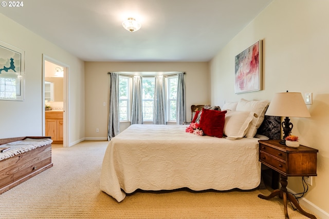 bedroom featuring connected bathroom and light carpet