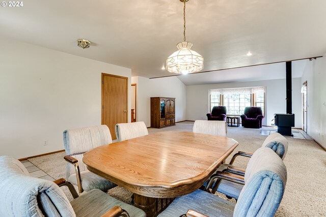 dining area featuring vaulted ceiling, a wood stove, and light colored carpet