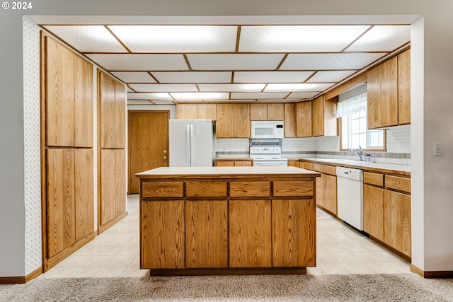 kitchen featuring a center island, sink, white appliances, and decorative backsplash