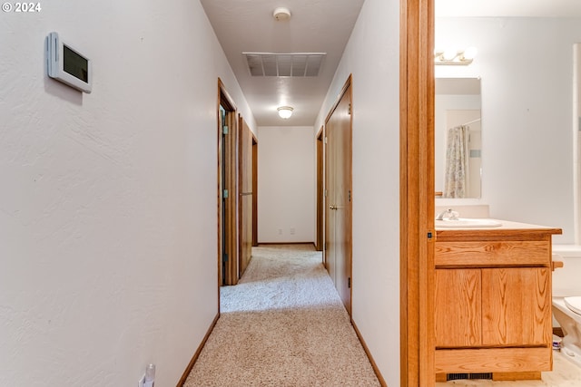 hallway featuring light carpet and sink