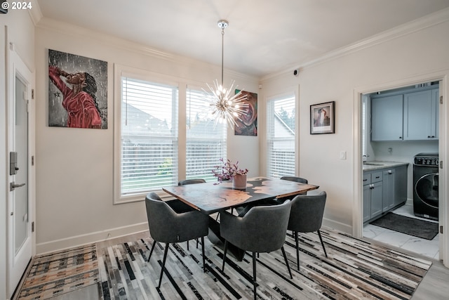 dining room with ornamental molding, light hardwood / wood-style floors, sink, a notable chandelier, and washer / clothes dryer