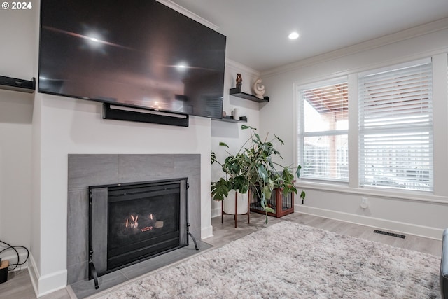 living room featuring light hardwood / wood-style floors, crown molding, and a fireplace