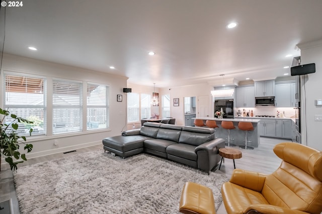 living room with plenty of natural light, a chandelier, and light hardwood / wood-style flooring