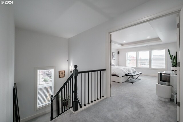 carpeted bedroom featuring a raised ceiling and multiple windows