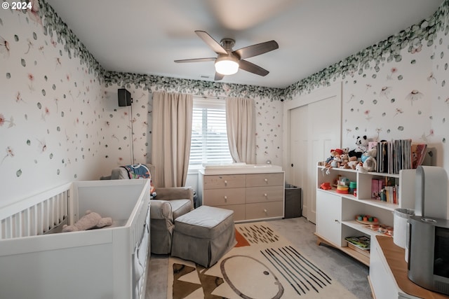 bedroom featuring ceiling fan, light colored carpet, and a crib