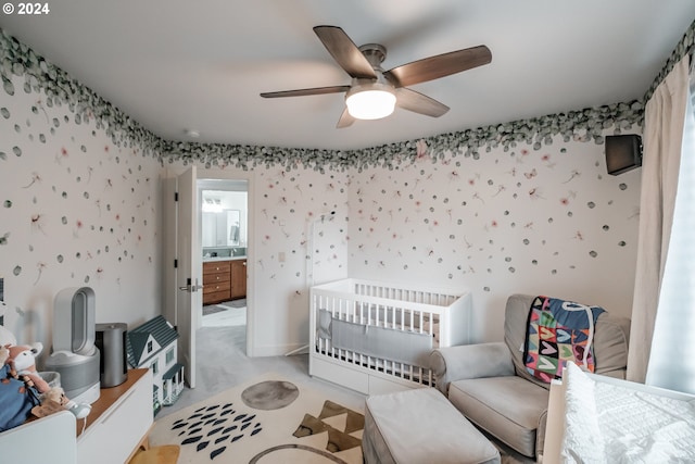 bedroom with ceiling fan, ensuite bath, light carpet, and a nursery area