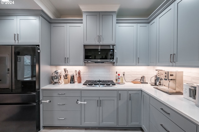 kitchen with backsplash, gray cabinets, and stainless steel appliances