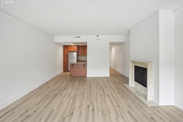 unfurnished living room with light hardwood / wood-style floors and crown molding