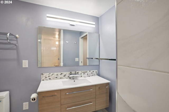 bathroom with vanity, toilet, and backsplash