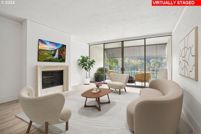 living room featuring a textured ceiling, light hardwood / wood-style flooring, and a wall of windows