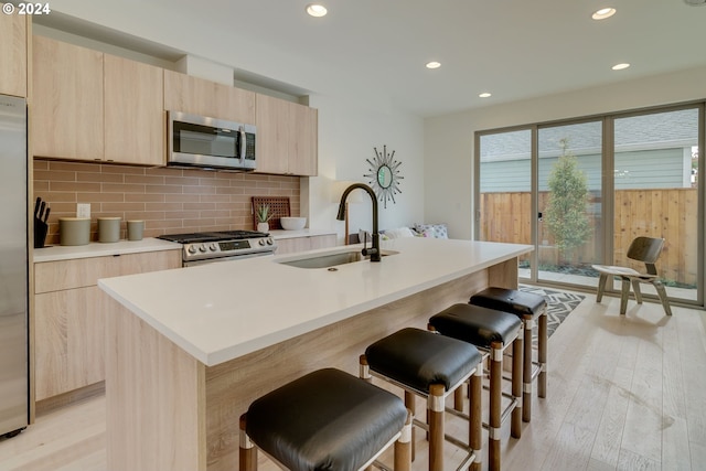 kitchen featuring light brown cabinetry, appliances with stainless steel finishes, light wood-type flooring, and plenty of natural light