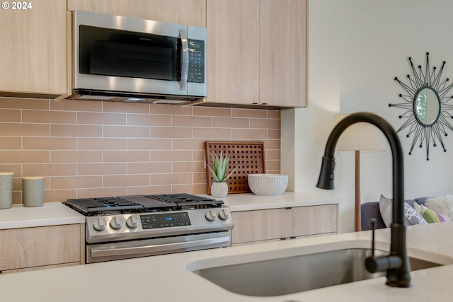 kitchen with sink, light brown cabinets, backsplash, and stainless steel appliances