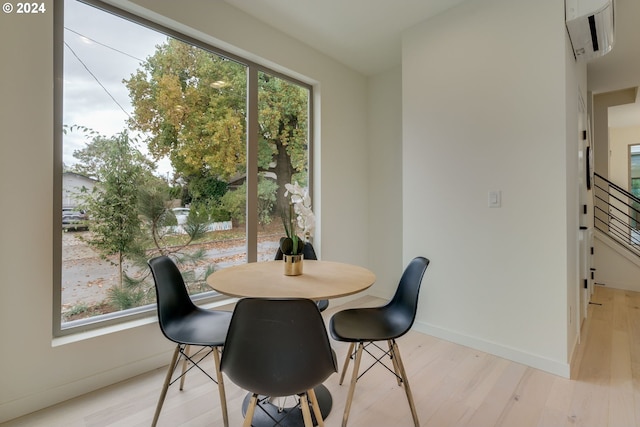 dining area with a wall unit AC and light hardwood / wood-style floors