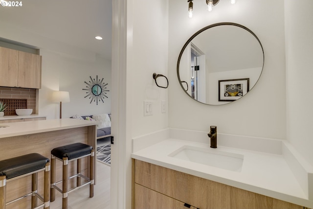 bathroom with backsplash, vanity, and hardwood / wood-style flooring