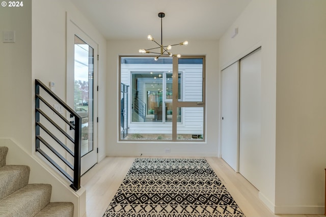 staircase with a wealth of natural light, light hardwood / wood-style floors, and an inviting chandelier