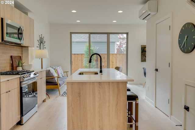 kitchen featuring a kitchen island with sink, appliances with stainless steel finishes, sink, tasteful backsplash, and a wall mounted AC