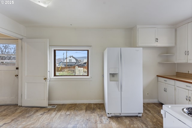 kitchen with plenty of natural light, white cabinetry, and white refrigerator with ice dispenser