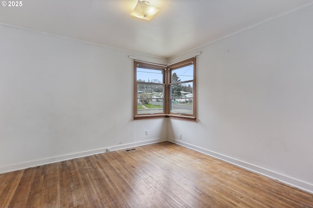 empty room with visible vents, baseboards, and hardwood / wood-style flooring