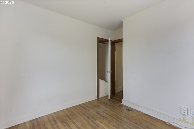 empty room featuring visible vents, baseboards, crown molding, and light wood finished floors