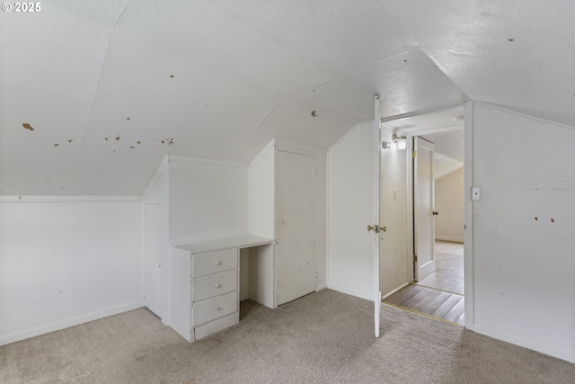 additional living space featuring lofted ceiling and light colored carpet