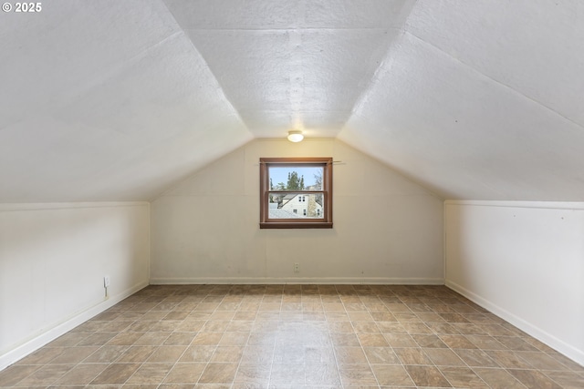 bonus room featuring vaulted ceiling, baseboards, and a textured ceiling