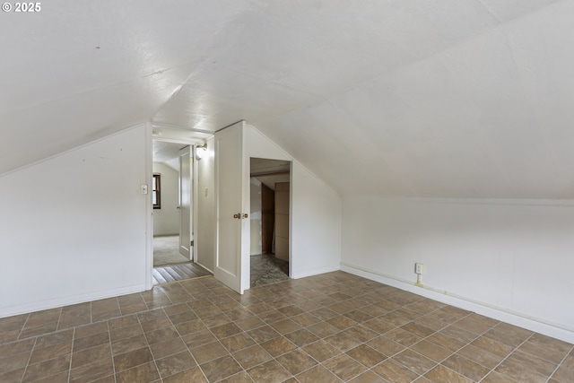 additional living space with baseboards and vaulted ceiling