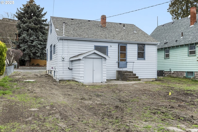 rear view of property with roof with shingles and a chimney