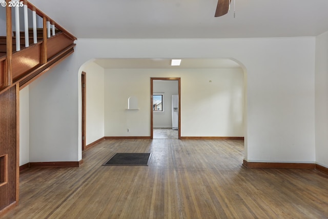 unfurnished room with baseboards, wood finished floors, arched walkways, and ceiling fan