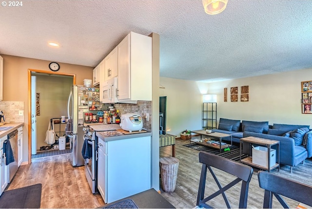 kitchen featuring white cabinetry, light hardwood / wood-style flooring, stainless steel appliances, and tasteful backsplash