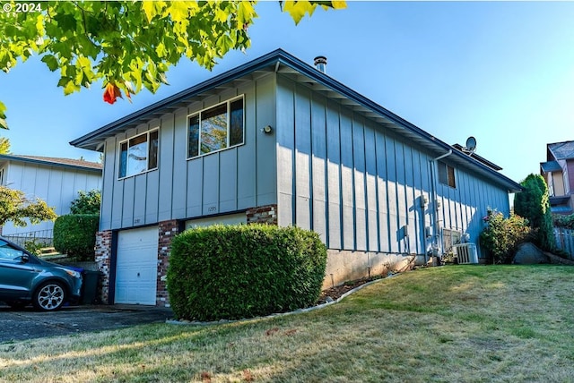 view of side of property with a lawn, central AC, and a garage