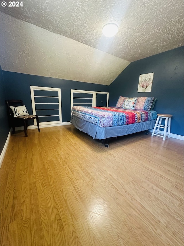 unfurnished bedroom featuring hardwood / wood-style floors, a textured ceiling, and vaulted ceiling