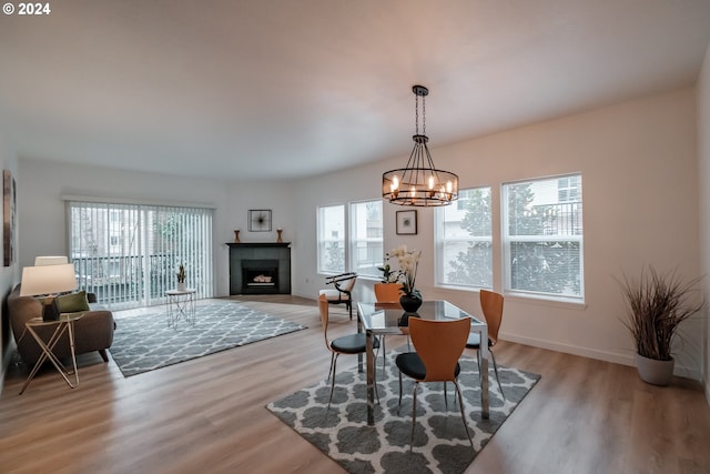 dining area with a chandelier, light hardwood / wood-style flooring, and a tiled fireplace