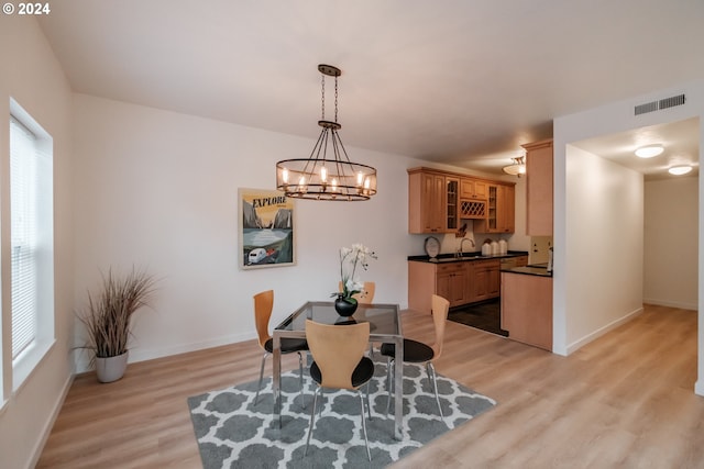 dining area with sink, light hardwood / wood-style floors, and a notable chandelier