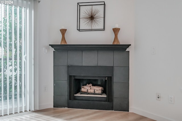 room details featuring a tiled fireplace and wood-type flooring