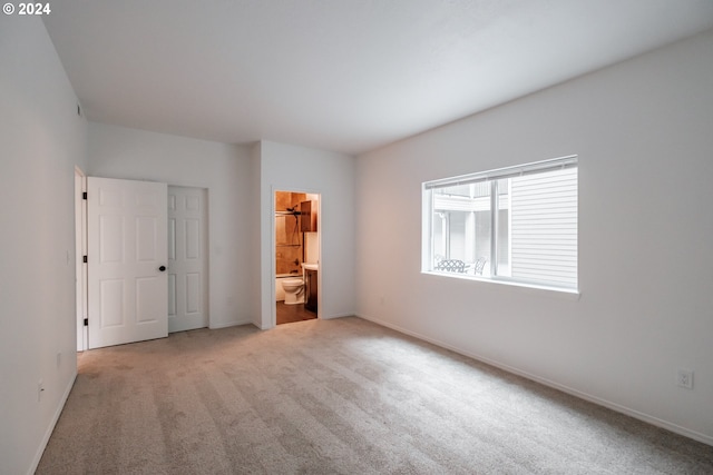 unfurnished bedroom featuring ensuite bath and carpet floors