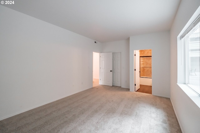 unfurnished bedroom featuring ensuite bathroom and light colored carpet