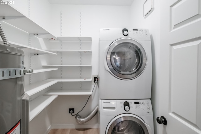 laundry area featuring wood-type flooring and stacked washer / dryer