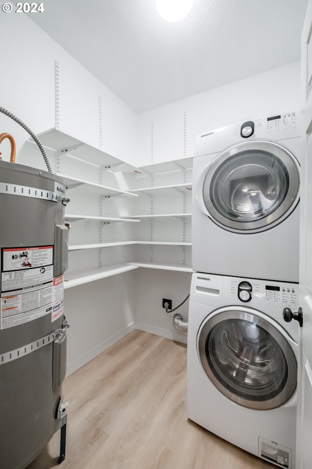 laundry room with secured water heater, light hardwood / wood-style floors, and stacked washer and clothes dryer